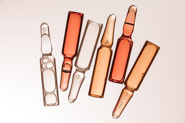 ampoules with different color serum on light background. - obrazy, fototapety, plakaty