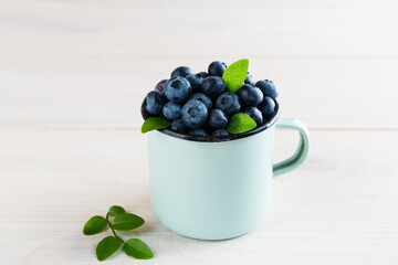 Blueberries in an iron mug on a wooden table.
