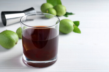 Delicious liqueur and fresh walnuts on white wooden table, closeup. Space for text