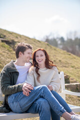 Smiling man and woman sitting on bench in nature