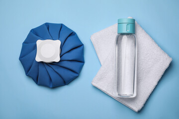 Bottle of water, cold compress and towel on light blue background, flat lay. Heat stroke treatment - obrazy, fototapety, plakaty
