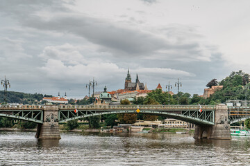 Fototapeta premium Scenic panorama of beautiful Prague Castle,Saint Vitus cathedral,Cechuv bridge over Vltava river.Famous tourist destination.Prague panorama on cloudy summer day.European cityscape urban travel concept