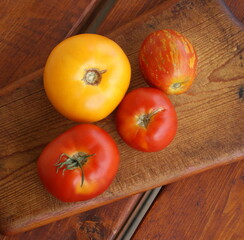 Four yellow and red tomatoes on a wooden board