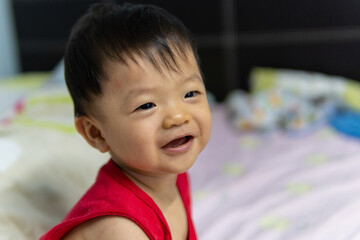 Portrait Adorable and happy Chinese baby boy child relaxing in bed