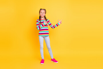 Photo of promoter little lady direct finger empty space wear striped shirt jeans shoes isolated yellow color background