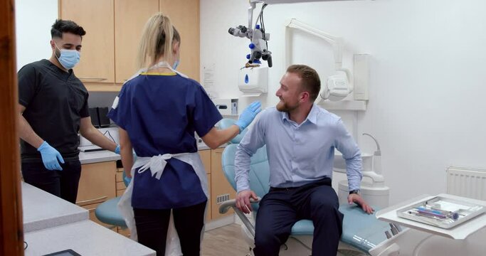 Caucasian male patient visiting dental room with female and male nurse 