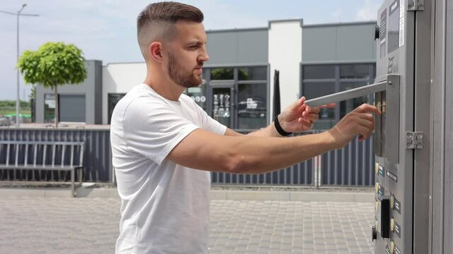 Man put plactic card for paying outdoors on self-service car wash