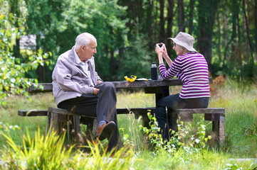 Senior elderly couple outdoors in park during summer