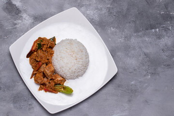 Stir-fried tuna with curry paste and steamed rice in a white plate