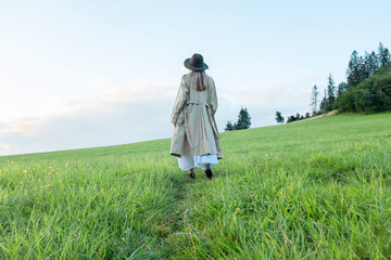 Happy woman enjoying sunset stay on the green grass on the forest peak of mountain. Fresh air, Travel, Summer, Fall, Holidays, Journey, Trip, Lifestyle.