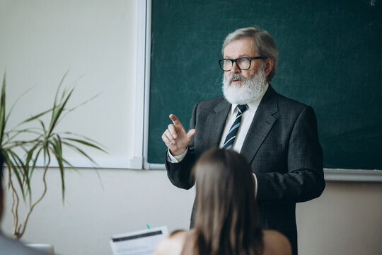 Elderly gray-headed man, professor, teacher and students at lecture, lesson at classroom, indoors. Concept of professional occupation, job, education
