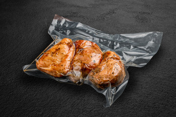 Vacuum-packed grilled meat, on a dark background, chicken fillet. Ready to eat. © GrumJum