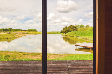 Scenic panorama calm small lake with wooden small bridge in peaceful Lithuania countryside