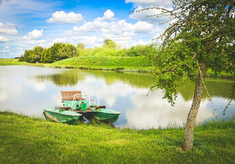 Green pedalo standing in private lake in sunny day in Lithuania countryside. Leisure activities outdoors concept.