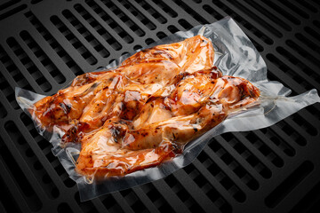 Vacuum-packed grilled meat, on a dark background, chicken wings. Ready to eat.