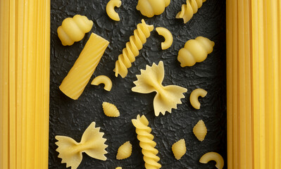Raw pasta varieties on black background