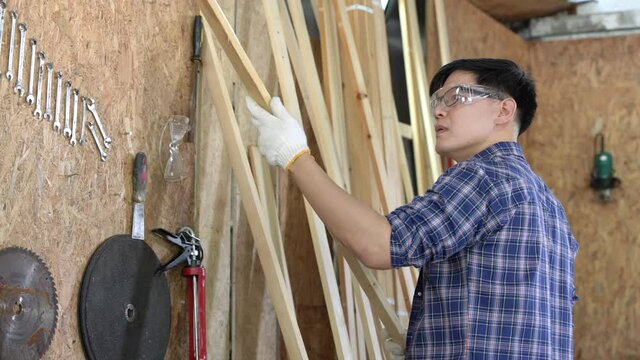A carpenter is using a planer. Male carpenter using planer in wood workshop.