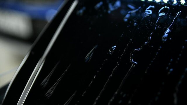 Video showing advantages of using ceramic coating on mini car hood. Hydrophobic effect on water pouring on metal surface
