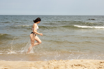 young beautiful girl running along the sand of the sea shore