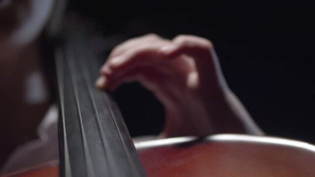 Woman's hand playing the cello, closeup. Cello strings closeup. Concept of playing a musical instrument