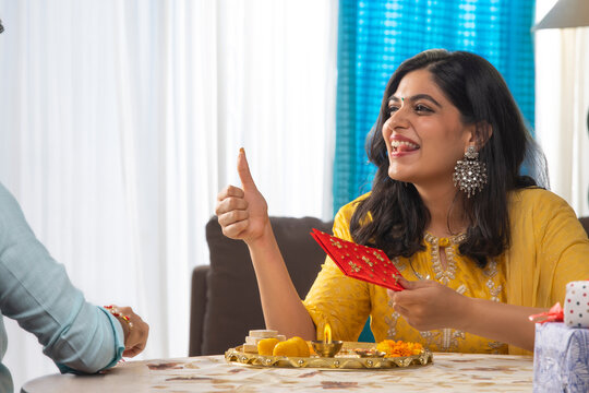 A HAPPY WOMAN TEASING BROTHER WITH RAKSHABANDHAN GIFT