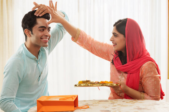 A HAPPY SISTER CELEBRATING TRADITIONAL RITUALS ON RAKSHABANDHAN WITH BROTHER