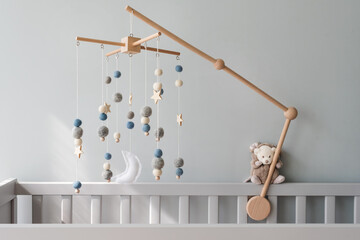 Baby crib mobile with stars, planets and moon. Kids handmade toys above the newborn crib. First baby eco-friendly toys made from felt and wood on gray background - obrazy, fototapety, plakaty