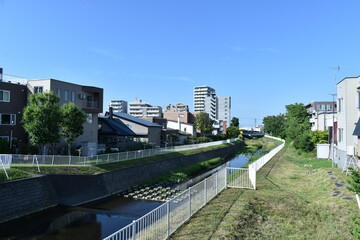 Fototapeta na wymiar Sapporo Japan August 1 2021 The peaceful neighboring landscape landscape along with the small canal with the clear blue sky in Sapporo Japan