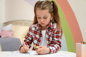 Little girl coloring antistress page at table indoors