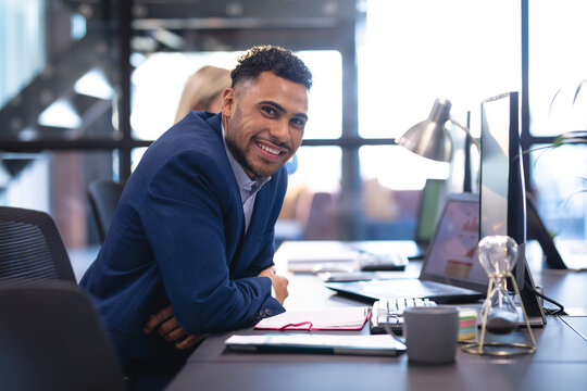 Portrait Of Businessman With Female Business Colleague Working At Desk Using Laptop