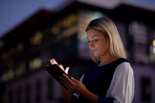 Caucasian businesswoman working at night using smartphone
