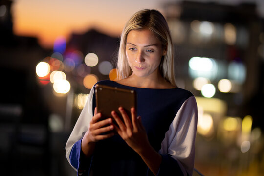 Caucasian businesswoman working at night using tablet