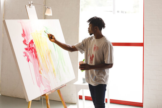 African american male painter at work painting on canvas in art studio