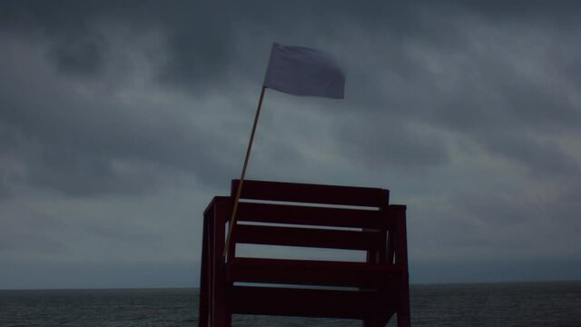 A waving flag on the lifeguard's tower on the beach on a windy and rainy day