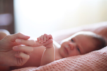 A newborn baby lies in her mother's arms. A beautiful baby of European appearance is sleeping.