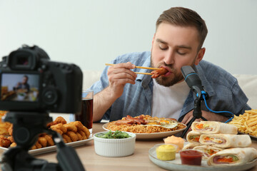 Food blogger recording eating show on camera against light background. Mukbang vlog