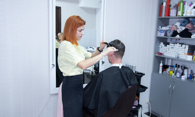 hairdresser girl cuts a guy's hair in a beauty salon