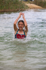 happy cheerful teenage girl splashes in water on vacation, horizontal.