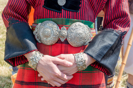 Silver jewelry. Traditional women's clothing. A young woman in Bulgarian folk costume. Silver ornaments, red robe and silver belt. Women's hands up close. Bulgarian folklore. Female hands.