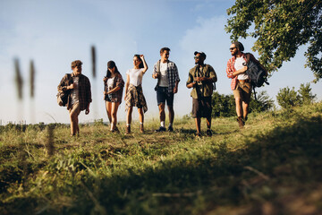 Group of friends, young men and women walking, strolling together during picnic in summer forest,...