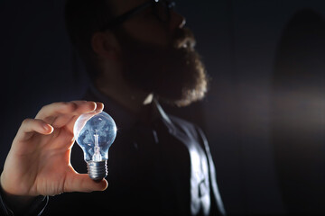 A bearded man in a suit holds an object in his hand. Concept of time and ideas. Aspiration and development.