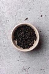 selective focus, natural black leaf tea. brewing in a clay bowl. vertical angle, macro. on a light background. for menus and cafes