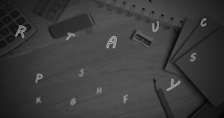 Multiple english alphabets floating against school stationary items on wooden surface