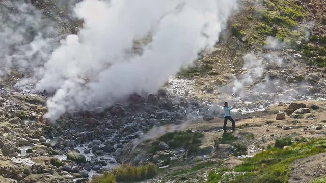 Hiking and eco tourism lady shoots video near huge geyser Explore travel with hike hikes in valley. Experience eco tourism at geyser with landscape views. Join our tourism adventure in kamchatka,