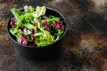 Bowls with mixed shredded salad lettuce leaves, on old dark rustic background  with copy space for text