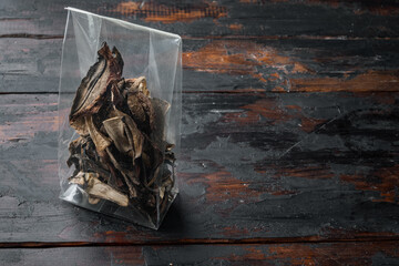 Mix of chopped wild dried mushrooms, on old dark  wooden table background, in plastic pack , with space for text  copyspace