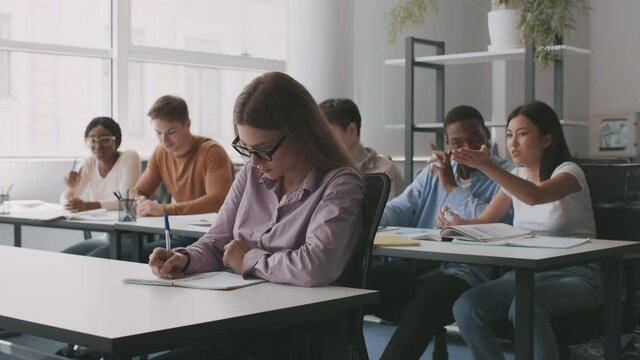 Bullying at college. Upsert lady nerd sitting apart of other students, rude groupmates laughing at her at classroom