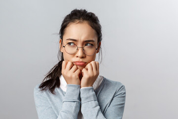 Close-up of gloomy offended young silly asian woman, sulking frowning upset, look left with envy or...