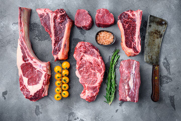 Raw beef meat steaks, tomahawk, t bone, club steak, rib eye and tenderloin cuts, on gray stone...