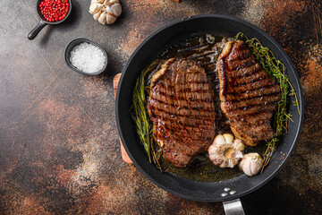 Grilled picanha organic  beef steaks on pan with herbs and garlic. Over old dark metall background,...